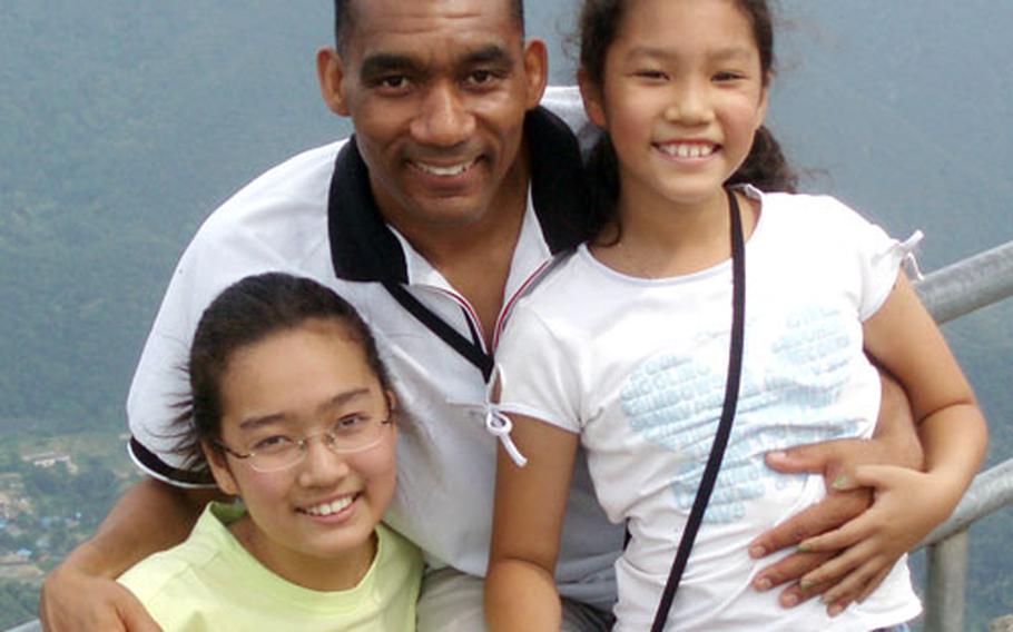 Air Force Lt. Col. Andrew Bossard poses with his daughters at Mt. Daduk in May. Bossard, who is African-American and Korean, was raised in South Korea until age 14 by his Korean mother. He now teaches at the Korean Air University.