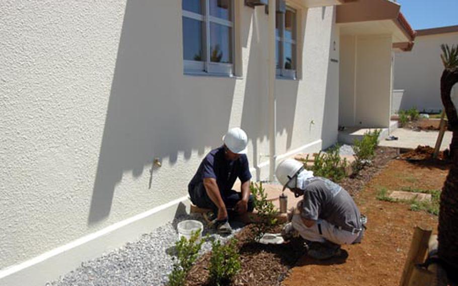 Workers plant shrubs along Washington Heights units on Kadena Air Base as part of a renovation program.
