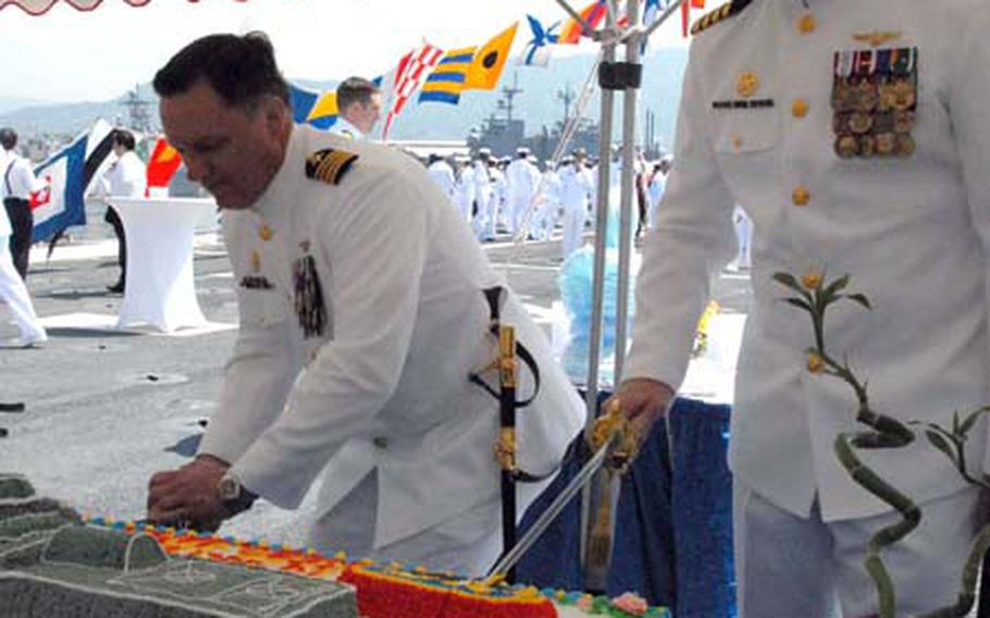 Capt. Dennis Mikeska, left, and Capt. Kent Whalen cut a cake during a command exchange ceremony at Sasebo Naval Base on Thursday. Whalen is the new commander of USS Denver, which sailed from the United States and was swapped with the USS Juneau after several weeks of work and a ceremony at the base.