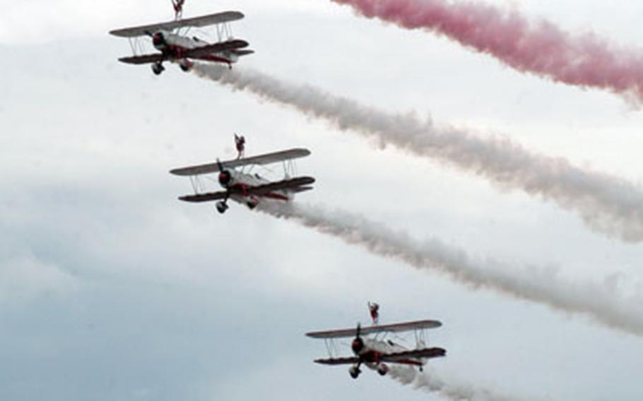 A formation of Stearman biplanes, qith "wingwalkers" on top of the wings, fly past crowds for the Flying Legends air show on Saturday at the Imperial War Museum in Duxford.