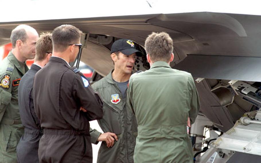 F-22 Raptor pilot Maj. Paul D. Moga (in the black hat) talks to other pilots about the Air Force’s newest fighter. The F-22 and other aircraft were grounded at this year’s Royal International Air Tattoo due to inclement weather.