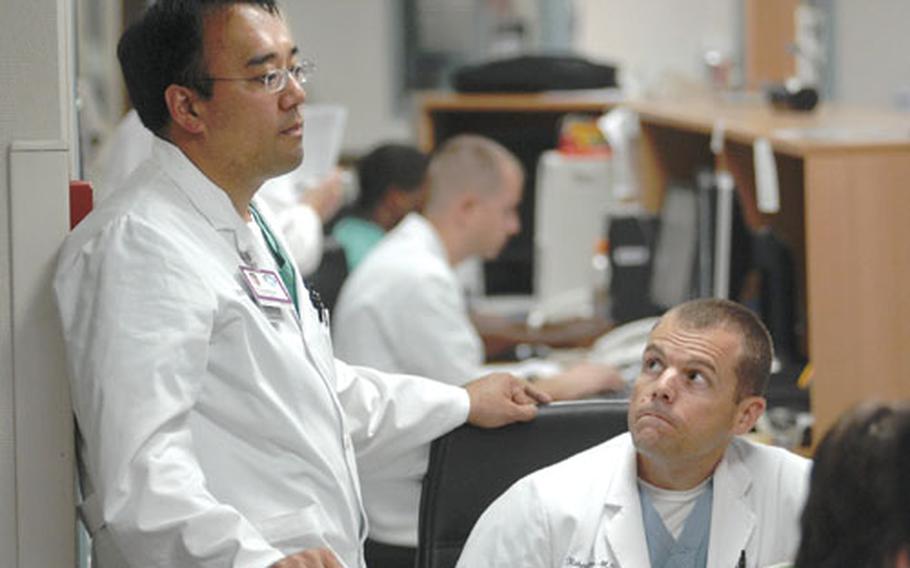 Air Force Lt. Col. (Dr.) Raymond Fang, left, a trauma surgeon at Landstuhl Regional Medical Center, discusses patient treatment with another doctor in the instensive care unit.