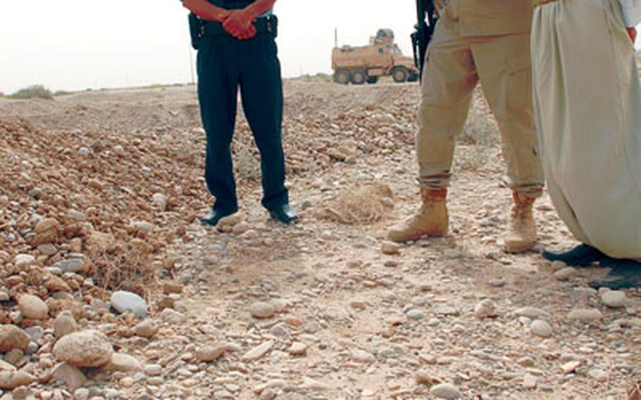 Jerry Pounds, center, a civilian Iraqi Police adviser with 23 years in law enforcement back in the states, looks at an artillery shell July 9 with the man who reported a cache of the explosives outside Kirkuk to Iraqi Police. The police are being urged to do more community policing.