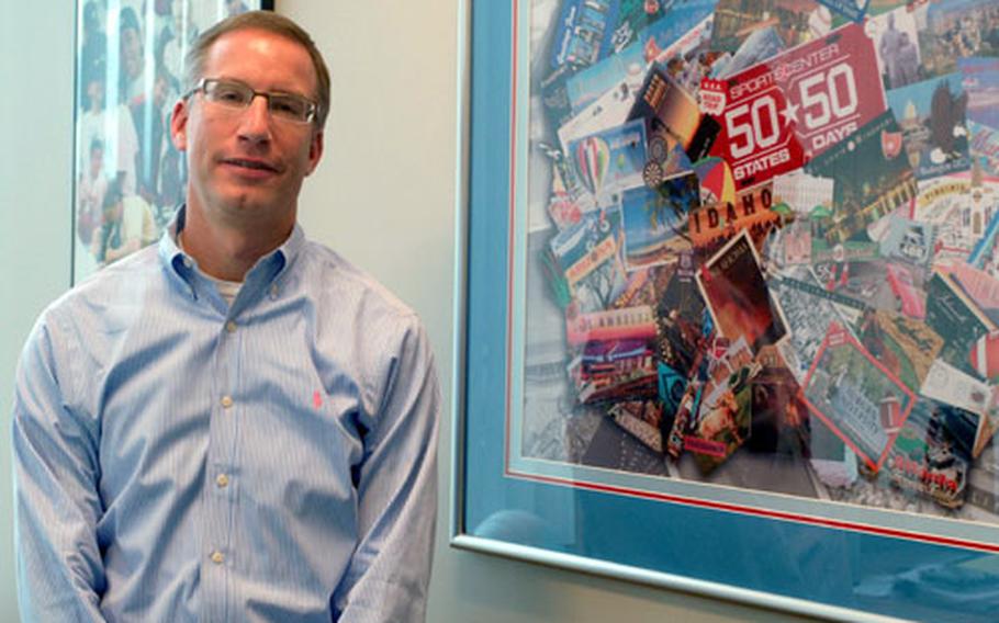 ESPN senior vice president Mark Gross stands by a commemorative collage from ESPN's 50 States in 50 Days summer series in 2005. The series included a stop at the 2005 All-Armed Forces Women's Softball Tournament at Petersen Air Force Base, Colo.