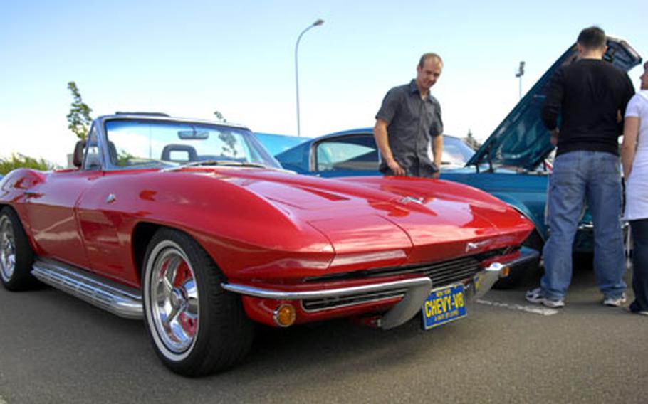 Automotive fans look under the hood of a classic Mustang parked behind a vintage Corvette Saturday at Spangdahlem Air Base's Motor Weekend car and motorcycle show. Motorcycle events, cars on display and a dynamometer for testing car performance highlighted the first day of the weekend event. A car show will be the main event on Sunday.