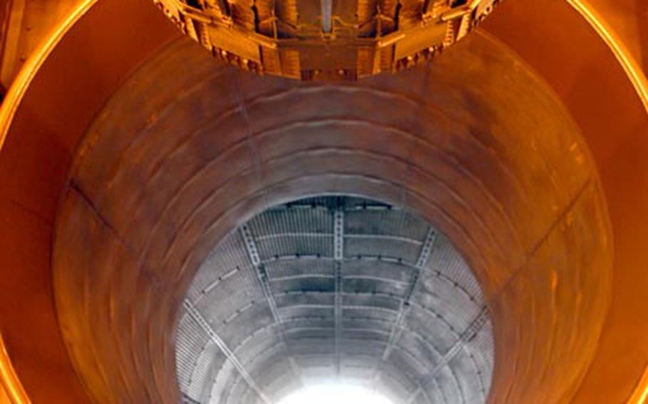 An F-15E Strike Eagle engine (top part of photo) points toward a long tunnel where the engine&#39;s afterburner will dissipate once it&#39;s at full power.