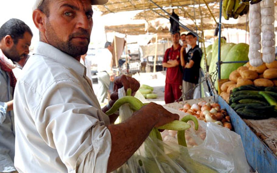 Ghazi Hajim places vegetables in a bag Monday for a customer at a Balad Ruz, Iraq, market. The Iraqi government has announced an upcoming offensive in an unspecified part of Diyala province, where the city is located. Hajim thinks the operation will bring stability and make it safer for potential customers to visit the market.