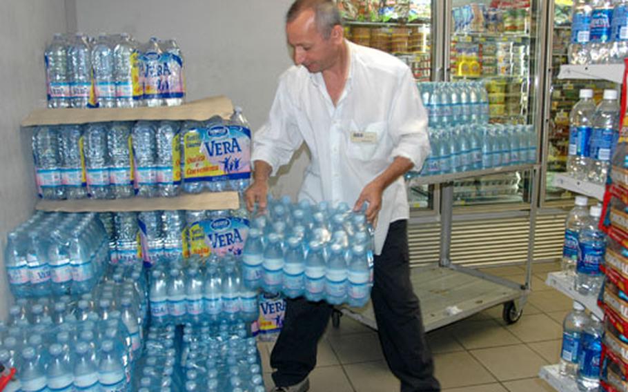 Carmine Desio, an employee of the Navy Exchange mini-mart at the Capodichino base in Naples, Italy, stocks bottled water for sale on Tuesday. The exchange plans on increasing its supply of bottled water in the coming weeks as Navy officials caution personnel who live off base to drink, cook with and even brush their teeth with bottled water.