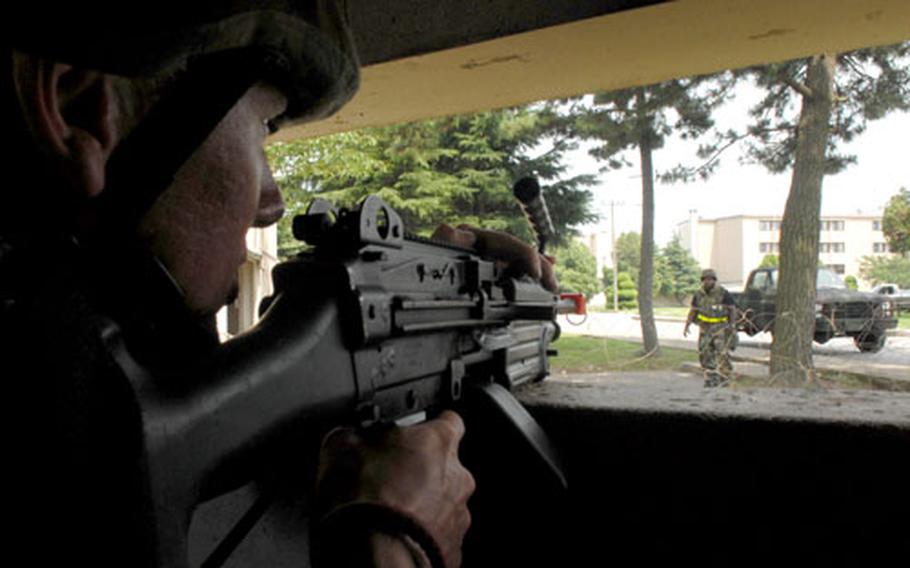Senior Airman Christopher Kaffer, 8th Security Forces Squadron, challenges Staff Sgt. Derrick Spencer with an M-249 on Tuesday at an entry control point. The mock face-off was part of a week-long readiness exercise for all U.S. airmen in South Korea.