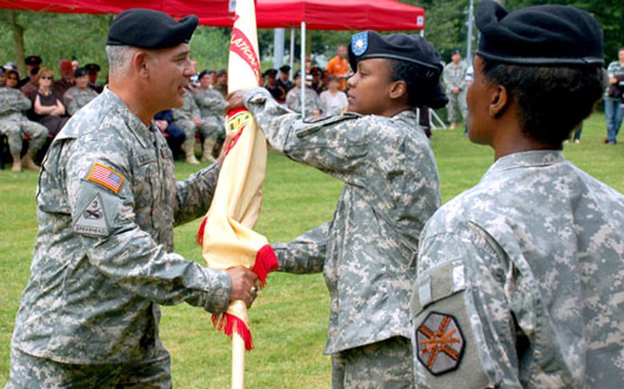 Col. James P. Drago, commander of U.S. Army Garrison Benelux, passes the colors to Lt. Col. Fern O. Sumpter, the incoming Schinnen, Netherlands, garrison commander, during a ceremony in June. At right, with back to the camera, is Command Sgt. Major Mary Brown, who assumed her post in May.