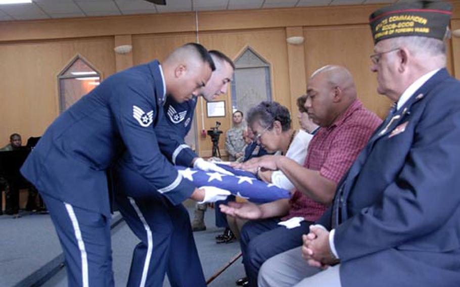 Sok Kyun Price, (right) wife of the late Master Sgt. (retired) James T. Price, and their son Steven, receives folded flags from members of the base honor guard during a memorial service held for Sergeant Price at the base chapel here July 29. Mr. Price passed away July 20, succumbing to injuries suffered in an accidental fall several weeks ago.