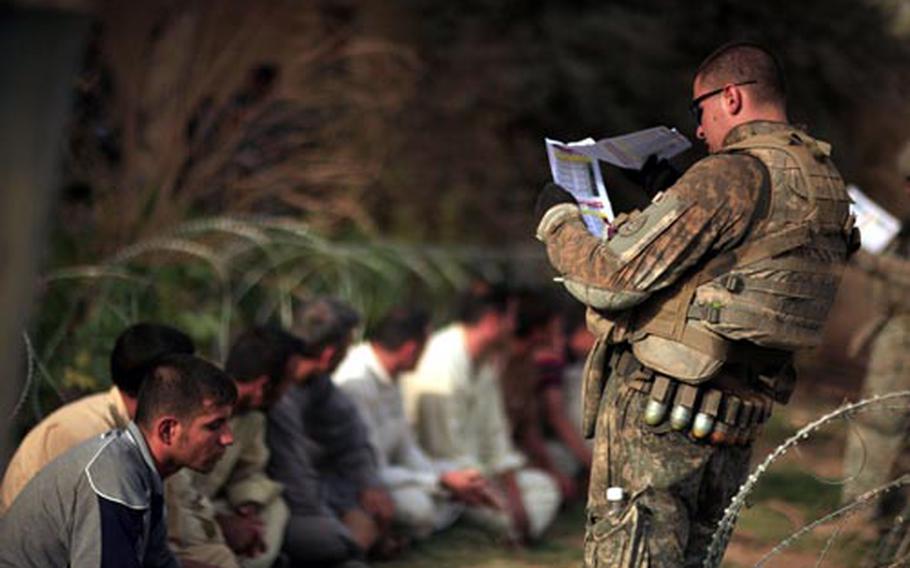 A U.S. Army soldier from Hammer company, 3rd Squadron, 2nd Stryker Cavalry Regiment checks a list of wanted terrorists as Iraqi men are temporarily detained while their identities are verified in Nahr al-Imam, about 90 kilometers (60 miles) north of Baghdad in Iraq's volatile Diyala province on Wednesday, July 30, 2008. Twenty suspected terrorists were detained in the sweep. Nearly 50,000 Iraqi police and soldiers were involved in a U.S.-backed operation against al-Qaida in Iraq in one of its last major strongholds near the capital, a senior provincial official said Wednesday.