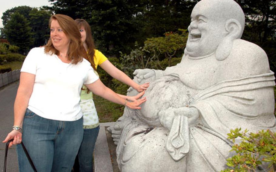 Military spouse Susan Hubbard rubs a Buddha statue's belly outside a Buddhist temple in Misawa, Japan, with her daughters, Amanda (back) and Elizabeth. The family was on the newcomers' tour put on every week by the Airman and Family Readiness Center. Rubbing the statue's belly is said in Japan to bring good luck.