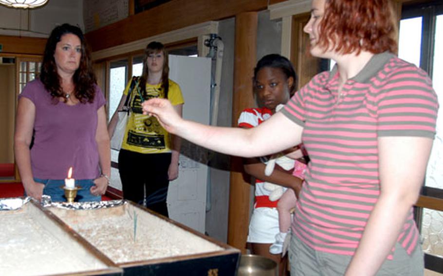 Jenni McIntyre, foreground, shows newcomers to Misawa the tradition of lighting a stick of incense in a Buddhist temple. A volunteer tour guide for the Airman and Family Readiness Center's local city tours, McIntyre encourages people to explore off base as much as possible.
