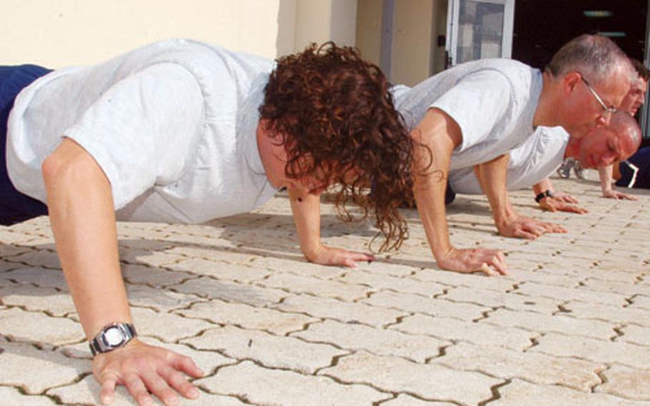 Tech. Sgt. Stephanie Chrisman, foreground, does push-ups outside Potter Fitness Center on Friday morning at Misawa Air Base, Japan, along with other members of the PT 100 Club — 138 airmen at Misawa who have achieved a perfect score in their annual mandatory fitness test. Also working out with Chrisman, right to left: Lt. Col. Geoffrey Crawley, Senior Master Sergeant David Varoskovic, and Airman 1st Class Nathan Carreon.