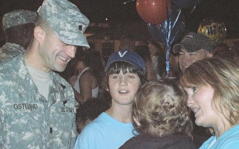 Lt. Col. Bill Ostlund, 2nd Battalion, 503rd Infantry Regiment commander, greets his family in a small island of calm as friends and family members of his soldiers rush around the field to embrace the troops returning from a 15-month deployment to Afghanistan.