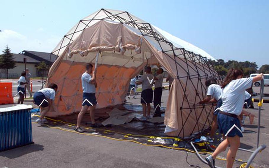 Airmen with the 35th Medical Group work quickly to erect a decontamination shelter at Misawa Air Base, Japan, on Thursday. The portable kits, being used Air Force-wide, are used to rid patients of hazardous chemicals before they are admitted to a hospital.