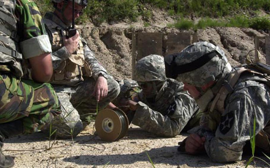 Pvt. Frederick Watkins, center, detonates a doughnut charge from behind a berm and blasts the hinges off a door Wednesday at Rodriguez Range, South Korea. Soldiers from the 2nd Infantry Division's 1st Battalion, 72nd Armor, Echo Company, showed South Korean soldiers how to set various breach charges during the combat engineer training event.