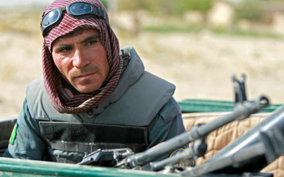 An Afghan police officer waits in the back of a pickup truck with a machine gun, before a recent meeting with tribal elders in the village of Osman Kheyl, in Kandahar province, Afghanistan. Unlike their U.S. counterparts, Afghan police serve mainly as paramilitary forces in the fight against Taliban insurgents in southern Afghanistan.