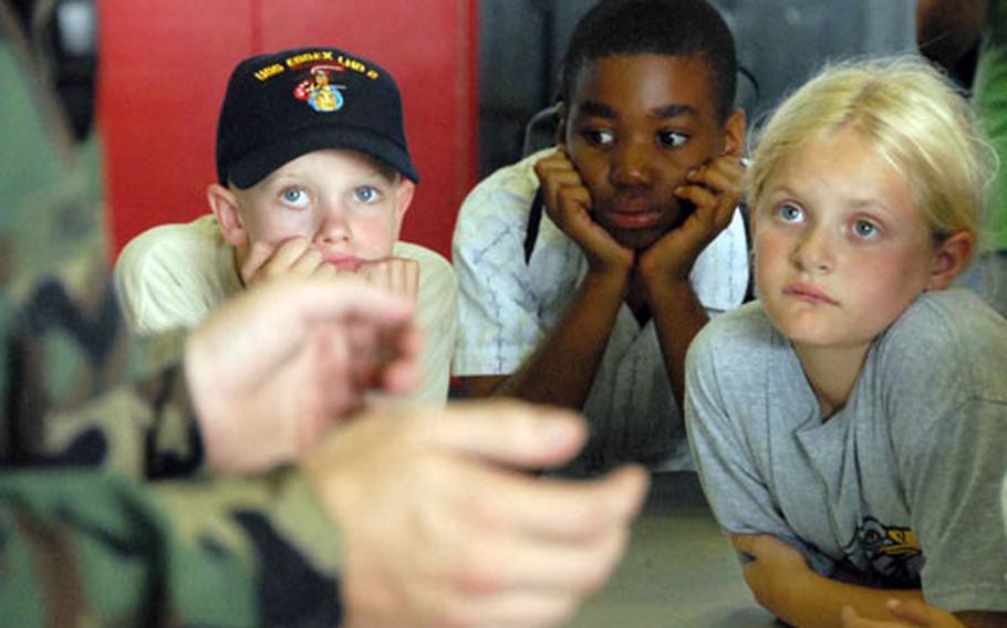 Chris Edwards, left, Darry Fitzgerald, center, and Teresa Steenman watch a security demonstration on fingerprinting and drug testing Thursday during a tiger cruise aboard the USS Essex.
