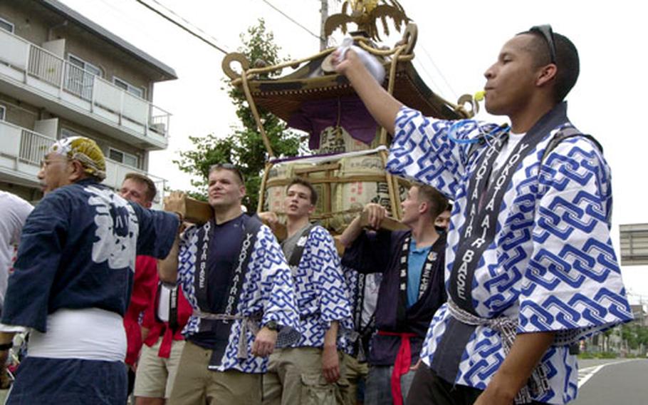 Yokota Air Base airmen carry a 1,000-pound shrine through the Fussa, Japan, streets Friday during the Tanabata festival. The airmen stepped to cadence supported by their own whistlers and percussionists.