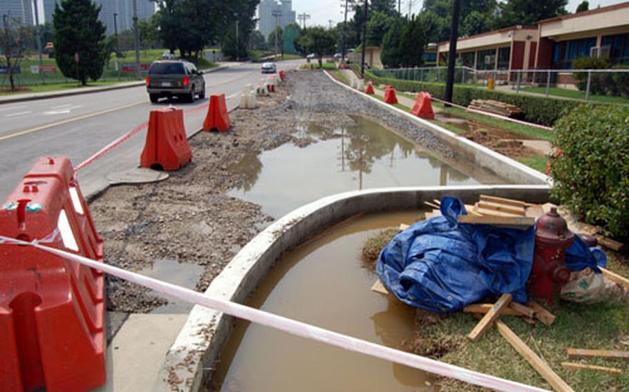 Heavy rains and standing water have made conditions to wet to complete the expansion of a parking lot and drop-off point at Seoul American Elementary School by the August 15 deadline.