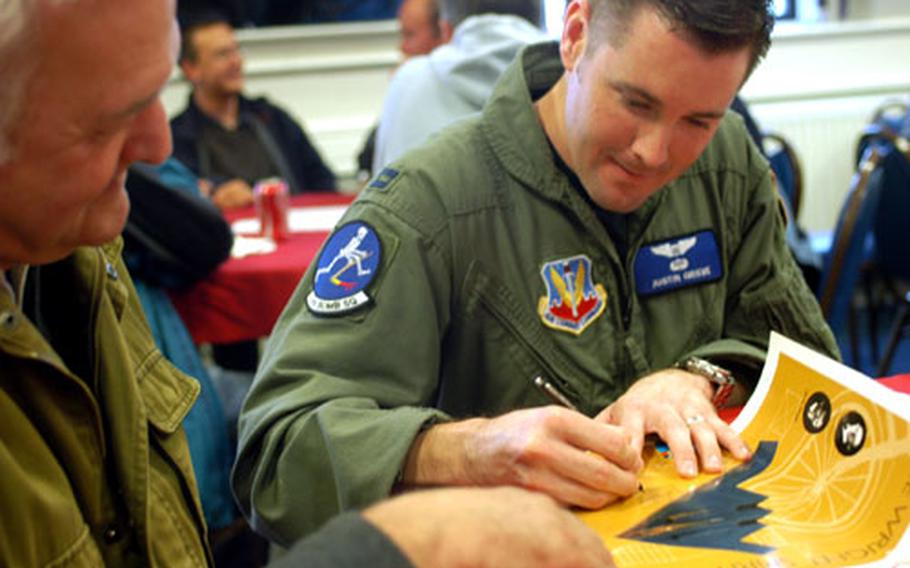 Capt. Justin Grieve signs a B-2 Spirit poster for Dennis Feltham, left, Wednesday at RAF Fairford. Grieve, a member of the 13th Bomb Squadron from Whiteman Air Force Base, Mo., recounted his miraculous ejection in from the stealth bomber in February during lunch with Feltham and other members of the Fairford Aviation Society.