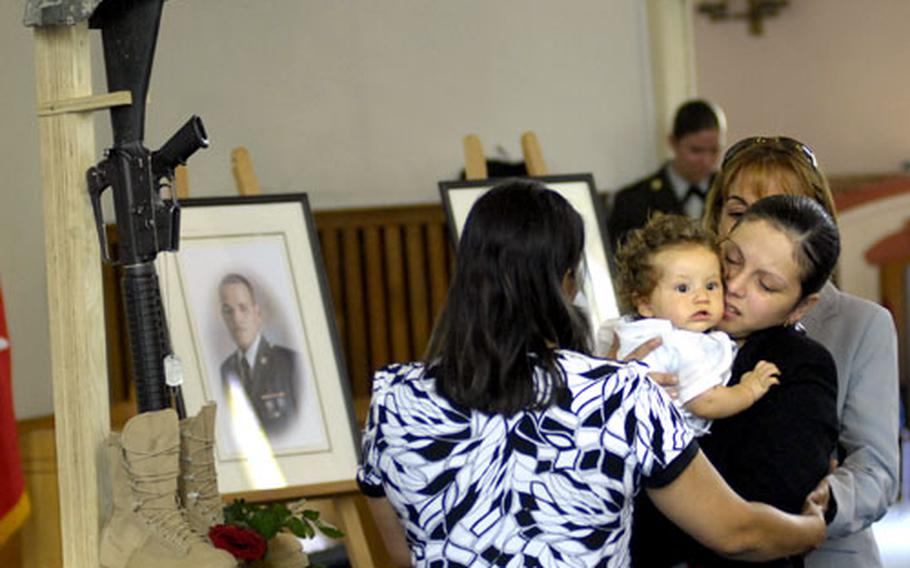 Melanie Nieves Atzmann holds her six month-old son Steven as she mourns the loss of her husband, Sgt. Jose Enrique Ulloa, at the conclusion of his memorial ceremony Thursday at the Mannheim chapel.