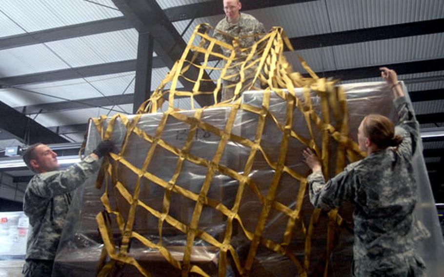 Soldiers with the 21st Theater Sustainment Command’s 66th Transportation Company drape a cargo net over humanitarian aid supplies headed for the embattled nation of Georgia. From left to right are Pfc. Jerry King, Spc. James Peterman and Pfc. Melissa Reagan.