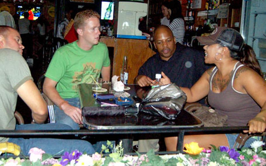 From left, Lt. Cmdr. Michael Davidson, Navy Lt. Nick Miller, Senior Chief Petty Officer Joseph Jones and Marine Staff Sgt. Mary Selvidge, all visiting Korea for the upcoming Ulchi Freedom Guardian exercise, enjoy drinks at Itaewon’s Goldfish Bar on Friday, the first night of the newly extended 3 a.m. curfew.