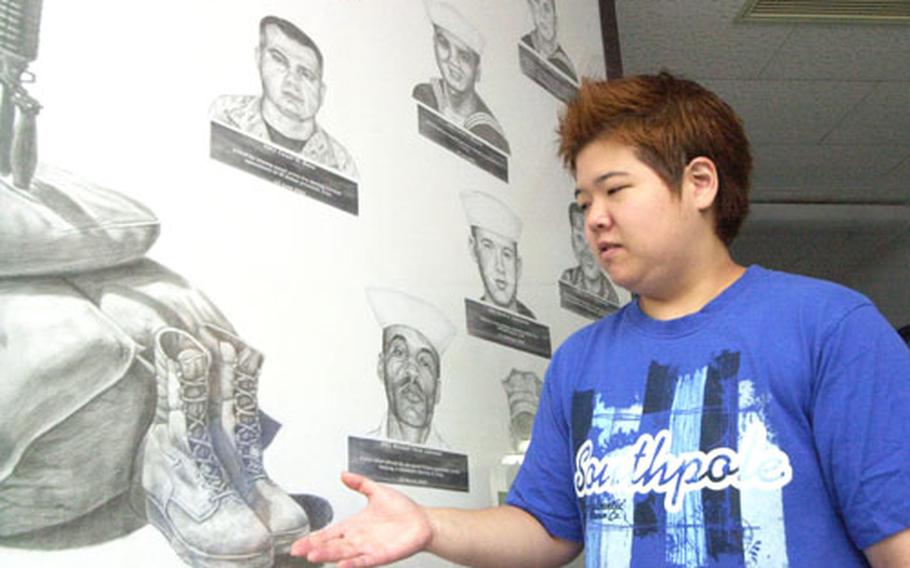 Petty Officer 3rd Class Youngran Jun explains the "Sailor's Cross," part of her mural sketched on a Yokosuka Naval Hospital wall dedicated to corpsmen who died in Operation Iraqi Freedom.