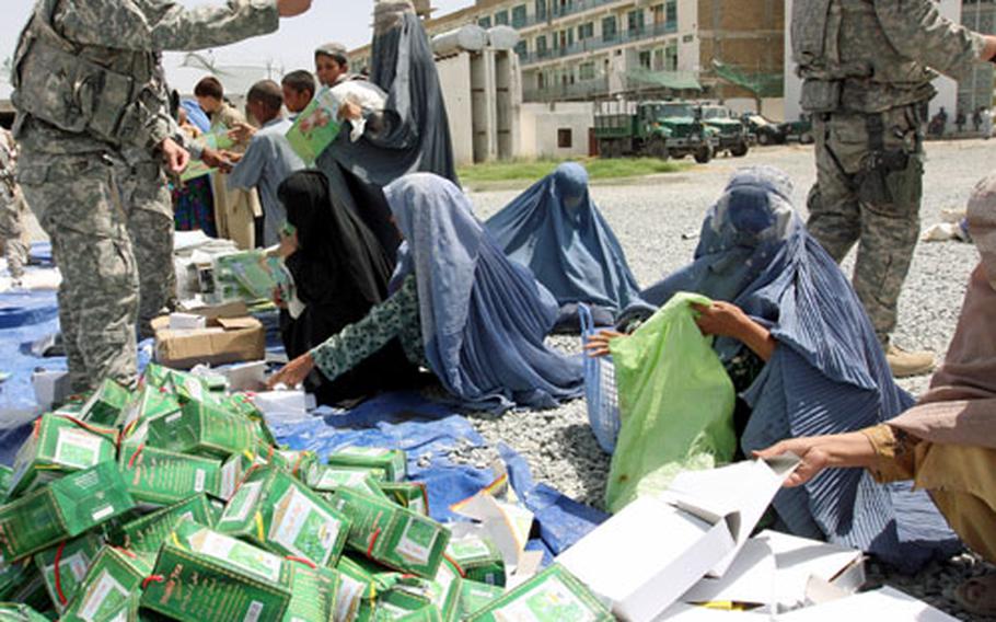 Afghan women grab coloring books and boxes of pencils as Sgt. Joe Parker, 25, of Corinth, N.Y., orders them to take only one of each item and then head for the gate during a humanitarian relief and medical aid mission in the southern city of Kandahar. But Parker’s order appears to have little effect, as the women grab whatever they can before being forced away.
