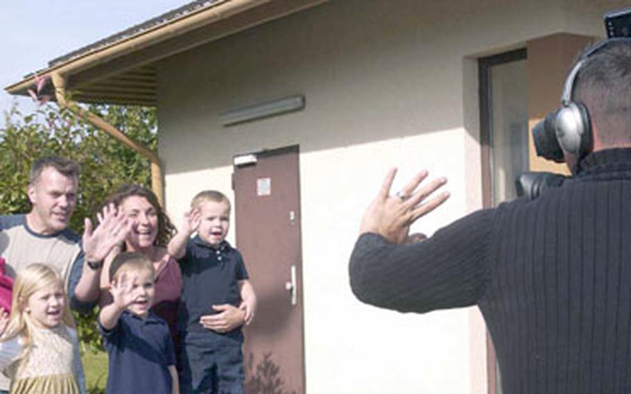 Kris Grogan, Army and Air Force Hometown News Service broadcast chief, reminds the Bond family to wave during a 2007 holiday greetings program taping at the Vogelweh Commissary in Kaiserslautern, Germany. A holiday greeting team will visit Europe again this year.