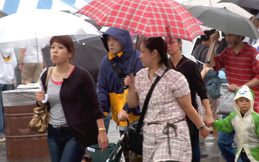 Japanese visitors walk through the rain with umbrellas drawn. Temperatures dipped into the upper 60s and a light, steady rain fell throughout the festival's opening day.