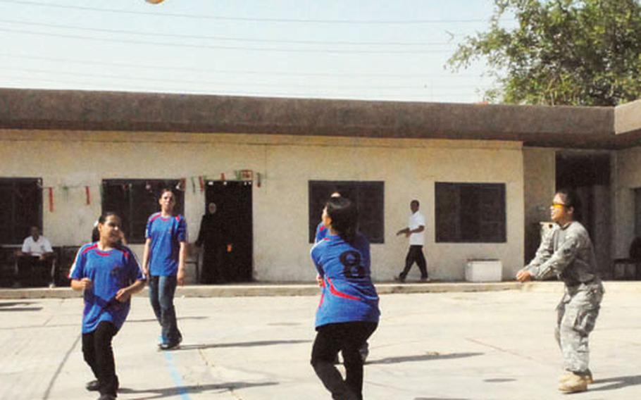 Capt. Thao Reed of the 1st Special Troops Battalion, 1st Brigade, 4th Infantry Division practices her setting skills with girls from the Al Basarah High School on Wednesday. The girls won the city volleyball championship last week.