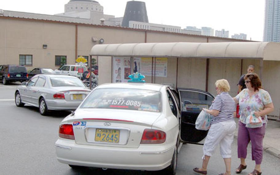 Army and Air Force Exchange Service customers get into a taxi at a taxi stand outside the Yongsan Garrison, South Korea, post exchange on Friday.