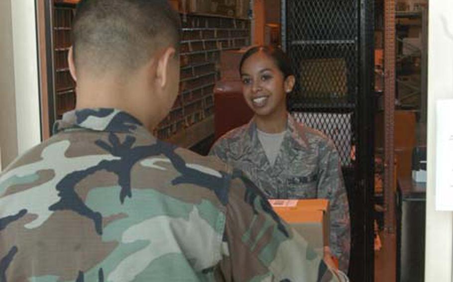 Senior Airman Casandra Franklin delivers a package Friday to Capt. Joseph Rountree at the customer service window at the Aviano Air Base military post office Friday. The base cut back on its customer service hours this month by about 10 percent, citing a need for training.