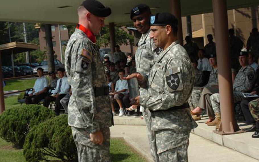 Brig. Gen. Joe Ramirez, outgoing 2nd Infantry Division assistant division commander for maneuvers, right, accepts a brass shell casing from Capt. Christopher Walsh, Battery B commander, 1-15 Field Artillery, during his patch ceremony Friday at Camp Red Cloud, South Korea. Maj. Gen. John Morgan, 2nd ID commander, is looking on beside Ramirez.