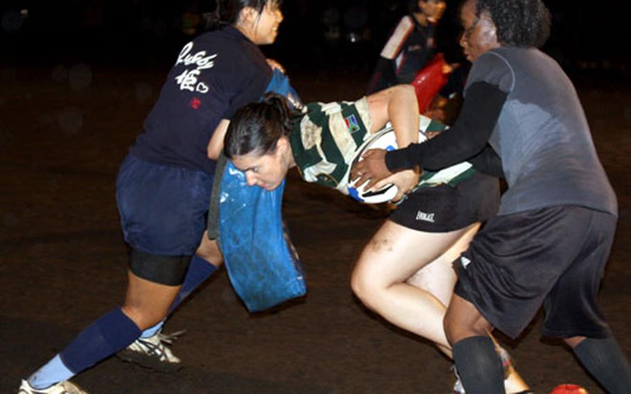 Emily Dewey, center, hands the ball off to Spc. Valery Valtrain, right, during rugby practice at Nippon Sports Science University in Aoba-ku, Yokohama City. This was the first official practice for the Phoenix, a Japanese women's rugby team, which has 11 American players participating this season.