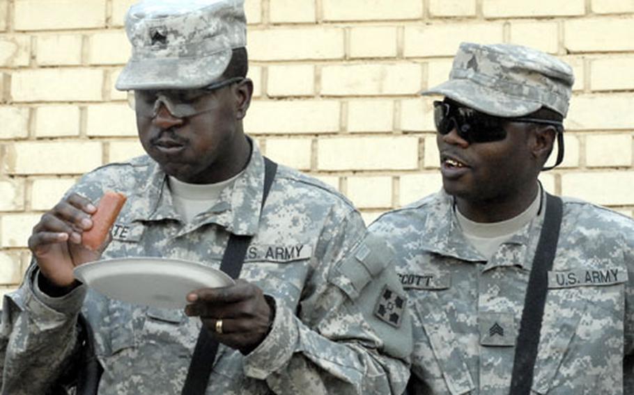 Sgt. Devon White, of the 4th Support Battalion, 4th Infantry Division’s Company A, chokes down a hot dog as a fellow soldier cheers him on during an eating contest. White fell short in the competition, downing only three foot-long hot dogs in five minutes, losing to a Charlie Company soldier, who ate five.