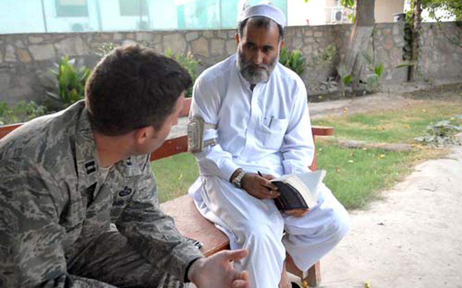 Engineer Ghaffar signs a copy of the book "Ghost Wars" during a visit to a U.S. base in Jalalabad. Ghaffar, whose exploits in firing the first CIA-supplied Singer missiles at Soviet helicopters were immortalized in the book, says his fighting days are over. Here, he talks with U.S. Air Force Capt. John Morath, a fellow Russian speaker.