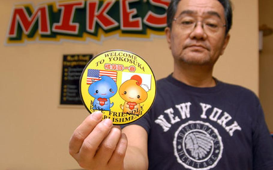 Local restaurant owner Hiroshi Watanabe shows off his new sticker that tells Americans at nearby Yokosuka Naval Base that his establishment is "base friendly."