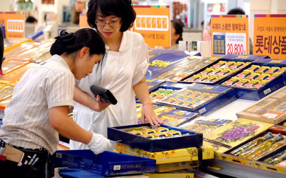 A customer at Lotte Mart in Seoul Station watches as a store employee checks a gift box of Spam. South Korea is one of the world's top consumers of Spam, which is a popular gift at Chuseok, one of the country's most important holidays.