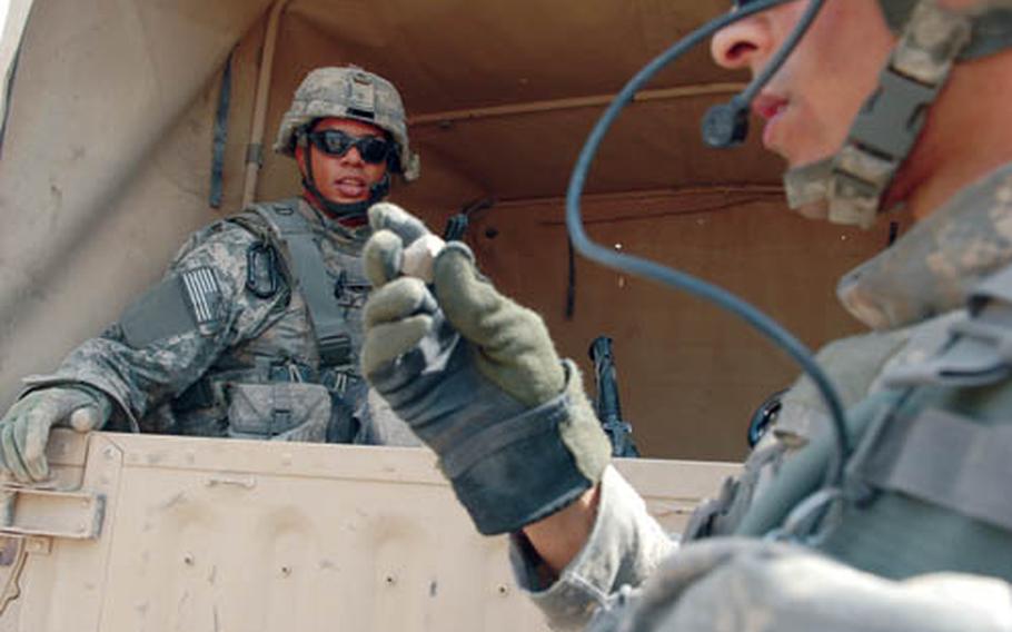 Cpl. James Anderson, background, looks at a piece of tile that an Iraqi boy threw at him Thursday while distributing water filters in Jisr Diyala, Iraq. Rock throwing is a growing problem in the area.
