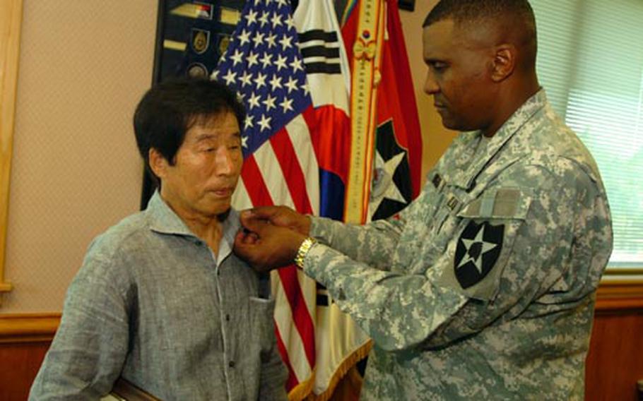 Yu Hu-son, left, receives a pin from 2nd Infantry Division commander Maj. Gen. John Morgan commemorating 50 years of service during a ceremony in August.