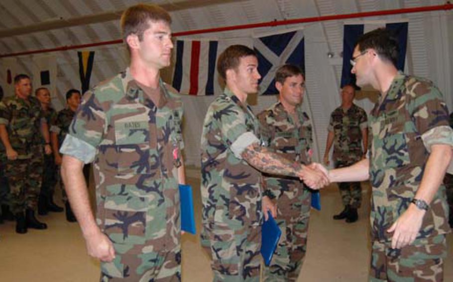 During an awards ceremony Aug. 29 on Guam, U.S. 7th Fleet commander Vice Adm. John Bird, right, congratulates Petty Officer 1st Class Nicholas Matics after awarding Matics a Bronze Star Medal. To the left and right of Matics, respectively, Petty Officer 1st Class Bryan Bates and Lt. James Vandevoort also received Bronze Stars.