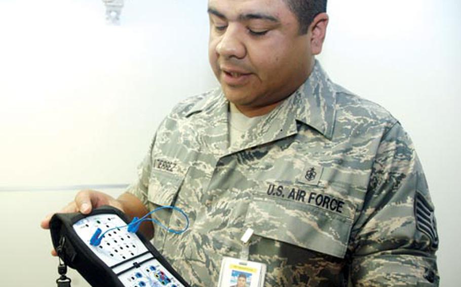 Tech Sgt. Dario Gutierrez, the noncommissioned officer-in-charge of cardiopulmonary services for the 18th Medical Operations Squadron, shows off a resperonic machine used to monitor a patient’s brain and heart activity at the sleep lab.