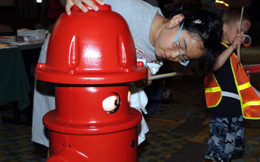 During a family day last June at Camp Humphreys, South Korea, 10-year-old Vanessa Engram (CQ) takes a look at “Pluggie” the talking fire hydrant – he shoots water too – and is a big hit with youngsters. Pluggie’s job is to help educate kids about fire safety. He’ll be making another personal appearance at Humphreys next month as part of annual Fire Prevention Week, set for Oct. 5th to 11th.