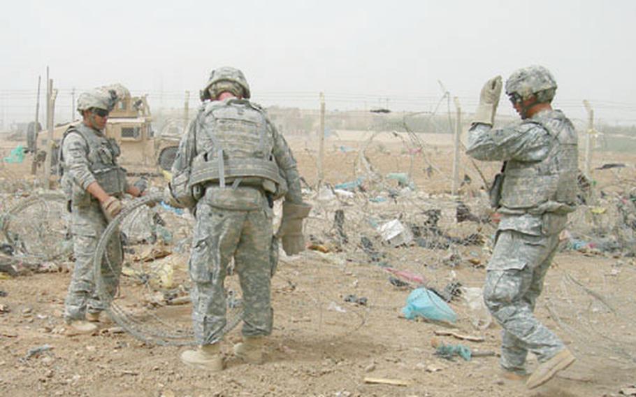 Soldiers with 1st Battalion, 22nd Infantry Regiment, Company E clear concertina wire from a field in Baghdad’s Jihad neighborhood. The curly razor wire collects trash and makes some residents feel like they’re living in a prison. The Americans hope removing it from Baghdad neighborhoods will bring a bit of normalcy back to the areas.
