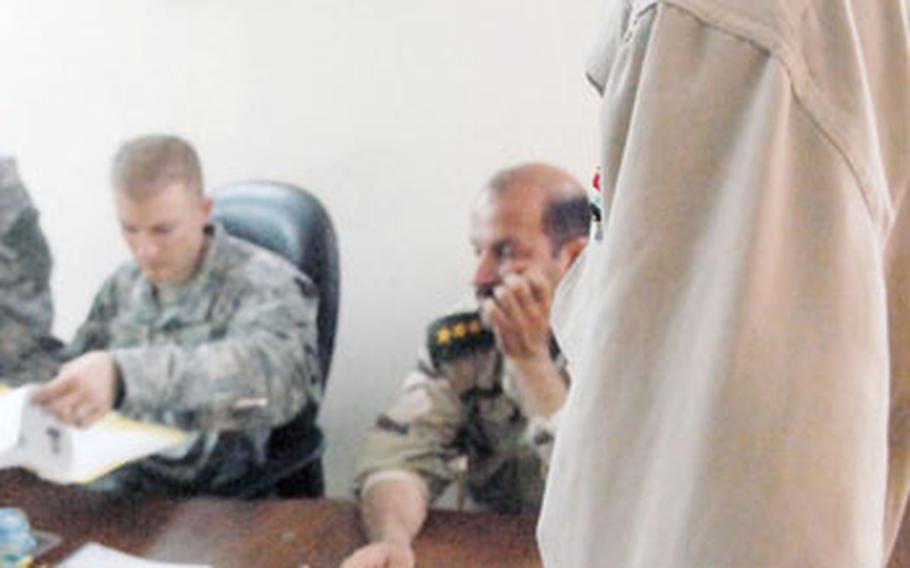 Achmet Taha Hamood, a "Sons of Iraq" member in Baghdad’s Ghazaliya neighborhood, waits for his file to be reviewed Tuesday by Capt. Thomas Melton, commander of Troop A, 1st Squadron, 75th Cavalry Regiment.